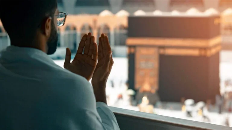 Home 54 Man praying in front of the Kaaba during June Umrah Deals 2026 pilgrimage journey