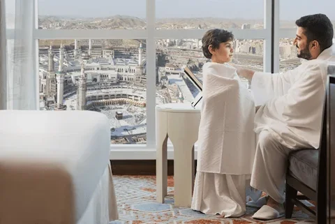 Blog 9 Umrah guide family preparing for pilgrimage in Makkah hotel room with view of Masjid al-Haram